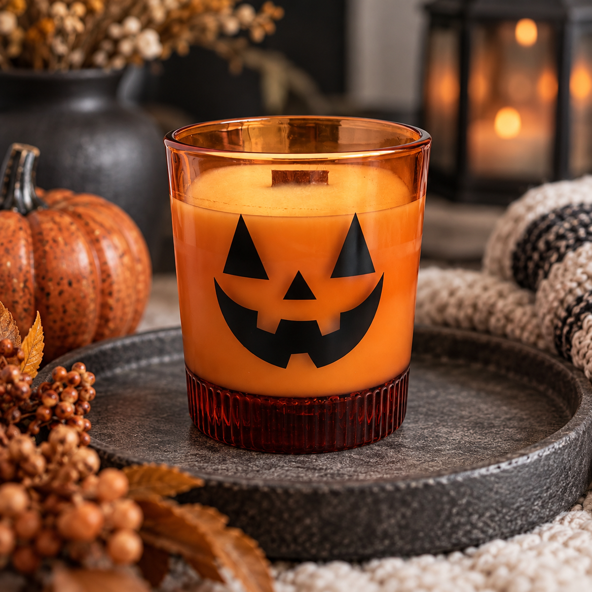 Orange jack-o'-lantern candle styled with pumpkin pie and autumn spices